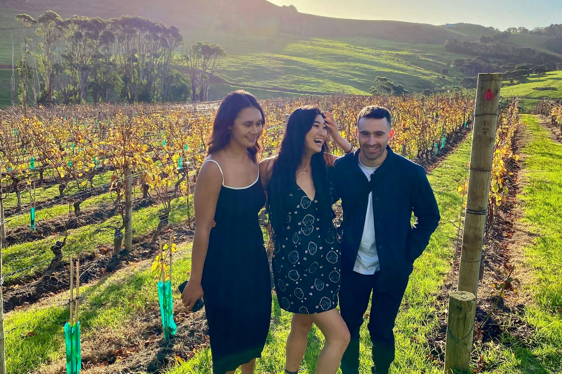Three friends smiling in a vineyard on Waiheke Island in Auckland